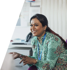 Image of a smiling brown skinned woman in a teal and red patterned shirt