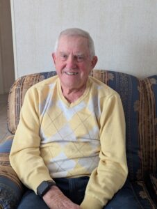 Glen Buhr, former TRAF Secretary-Treasurer, sits in his home wearing an argyle sweater
